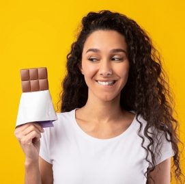Mulher sorri enquanto segura chocolate