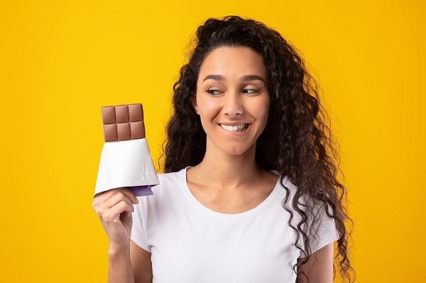 Mulher sorri enquanto segura chocolate 