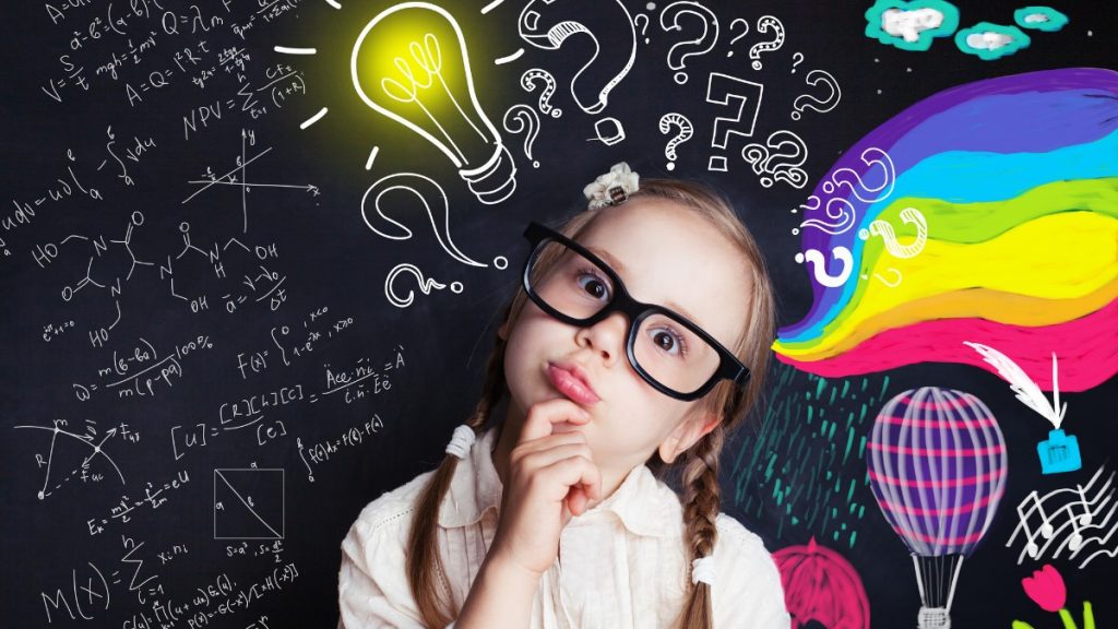 Menina loira usando óculos com cara de dúvida e, ao fundo, um fundo tipo quadro negro com desenhos de pontos de interrogação, fórmulas e arco-íris