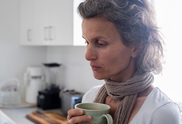 Mulher na perimenopausa preocupada tomando um chá 