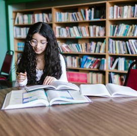 Mulher, adulta, de óculos estudando em uma biblioteca