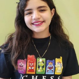Valentina Meira, 12 anos, usando uma blusa preta com estampas coloridas e uma tiara preta.