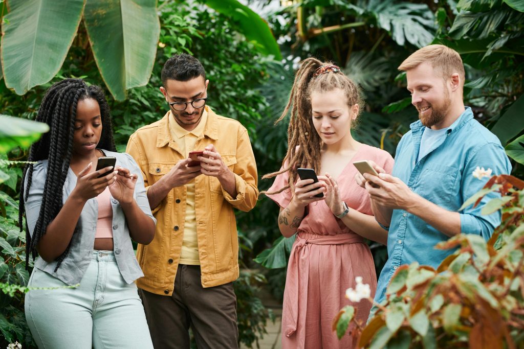 Grupo de jovens usando o celular em meio à natureza