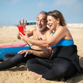 Casal de idosos curtindo uma manhã de surf enquanto fala ao celular